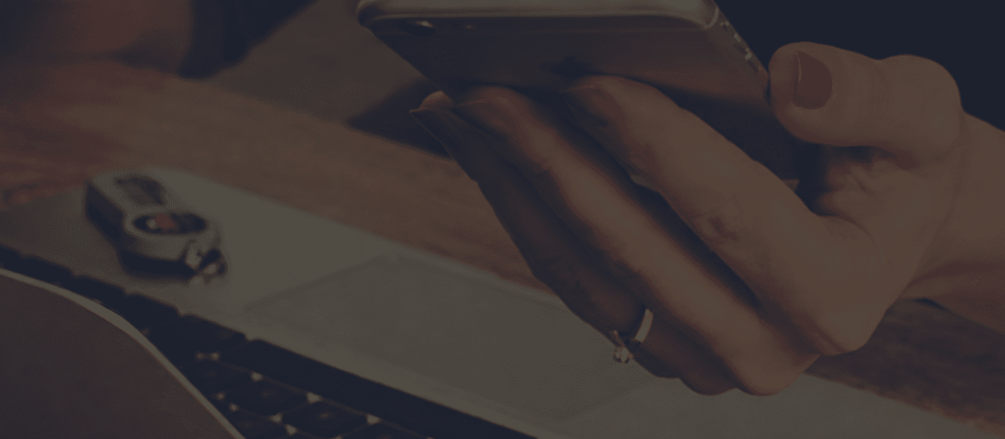 Person holding phone over laptop — contact Searcher Properties